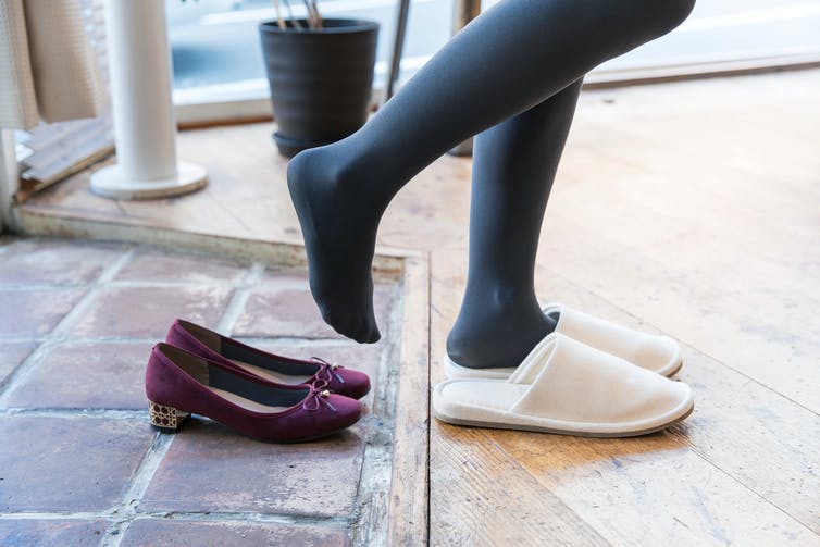 A woman takes off her shoes at the entrance of her house